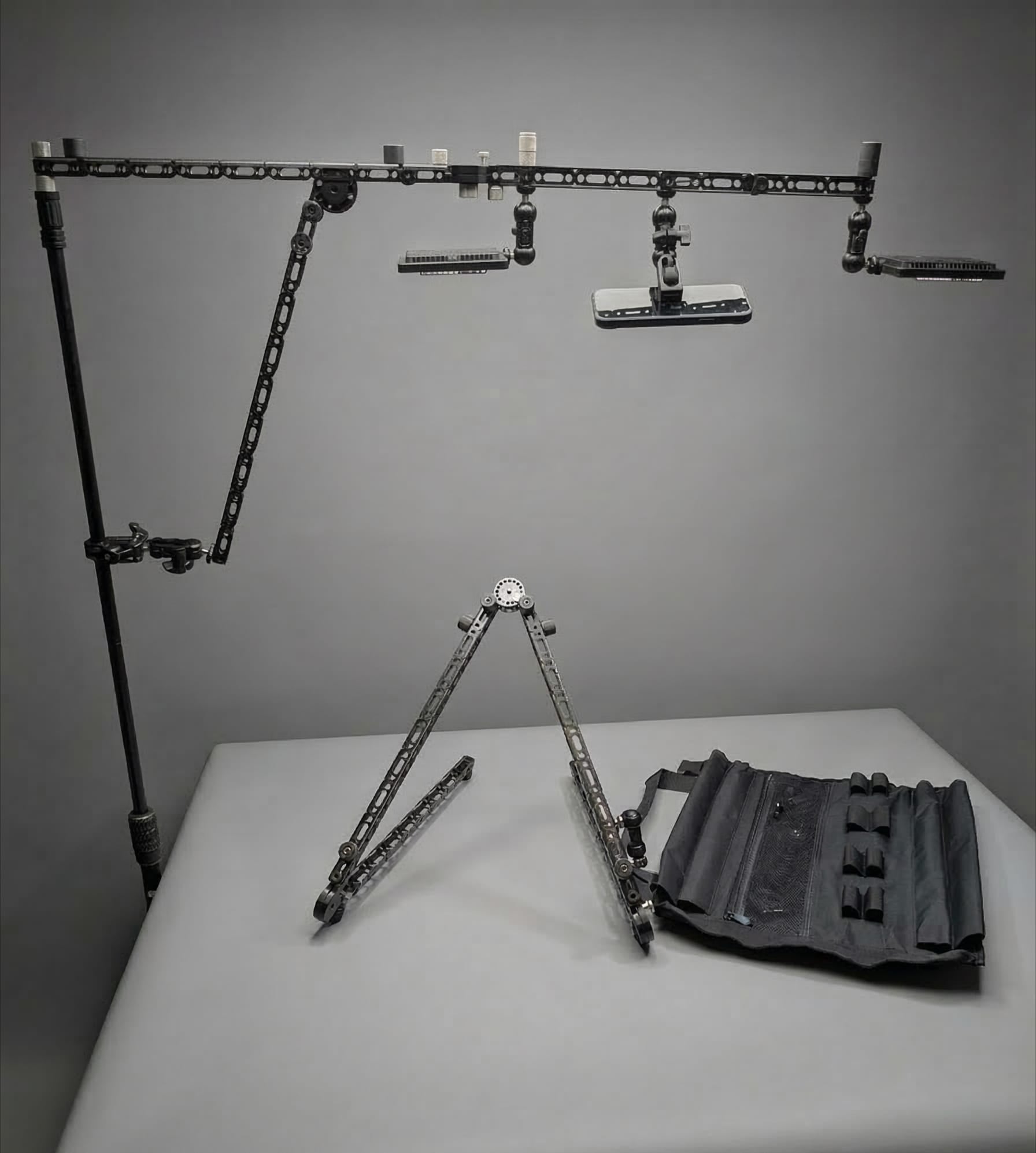 Manofold modular overhead camera rig built from structural rails and standard mic stand bases, supporting lights and camera accessories for photography and video production.
