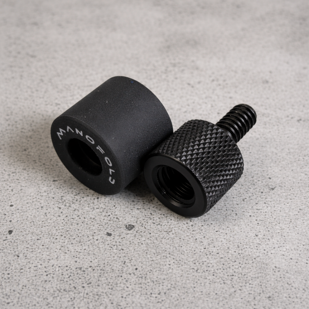 Two black knurled knobs on a gray concrete surface
